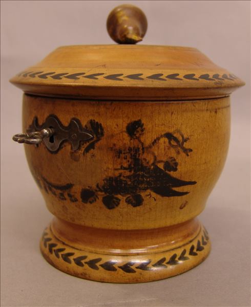 A Continental turned wood tea caddy Of circular section, with painted decoration, the hinged cover