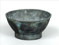 A bronze bowl, possibly Chinese With moulded rim, standing on a shallow foot. 11.5 cms diameter.