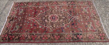A Hamadan wool rug The wine red field enclosing a central medallion with urn spandrels and
