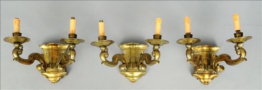 A set of three brass twin branch wall lights Each serpentine back plate issuing twin scrolling