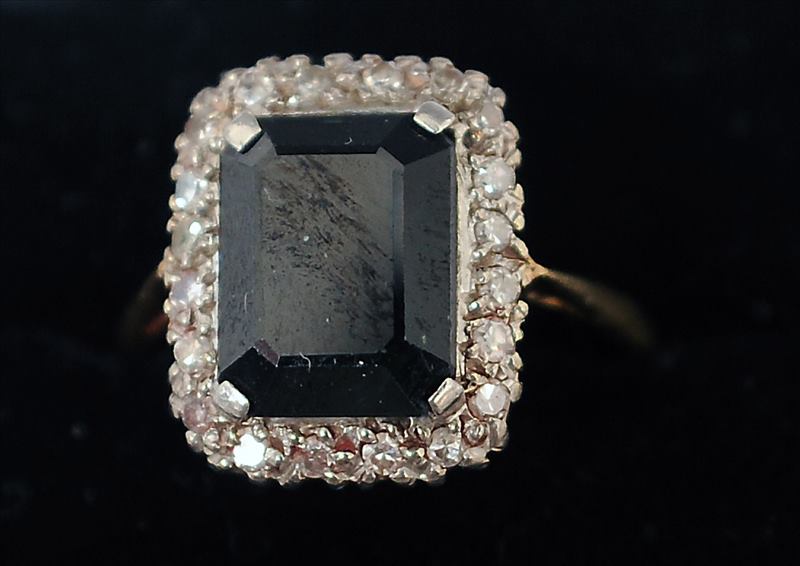 An 18 ct gold and platinum sapphire and diamond ring The central emerald cut stone bordered by a row