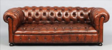 A leather upholstered buttoned Chesterfield settee Upholstered in brown leather, standing on bun