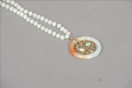A Chinese grey jade bead necklace Hung with a russet jade and unmarked gold roundel, the stone set