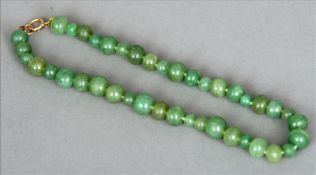A carved jade bead necklace Of varying sizes with yellow metal clasp. 43 cms long overall. Generally