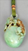 A Chinese carved green and russet jade pendant pebble Modelled as a mythical beast. 7.5 cms long.