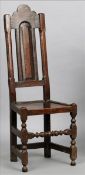 A 17th century oak panel back hall chair The shaped top rail above the slender panelled back flanked