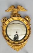 A Regency giltwood wall glass The convex plate housed in an oval frame surmounted with an eagle