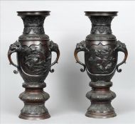 A pair of large Japanese bronze vases Each twin mask headed handled vessel decorated to the centre
