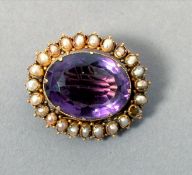 A Victorian unmarked yellow metal amethyst and seed pearl pendant The central facet cut stone