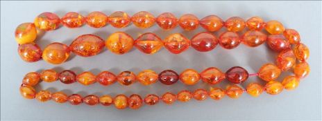 A large amber bead necklace Each bead of oval form. Approximately 98 cms long. Possibly re-strung.