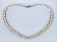 A cased cultured river pearl necklace Set with a florally cast clasp. Approximately 42 cms long.