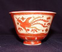 A Chinese porcelain tea bowl Decorated in gilt on a red ground with stylised phoenix within precious