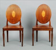 A pair of George III mahogany shield back hall chairs Each back with central patera inlay above