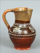 A slip decorated pottery carafe, probably French Impressed mark to handle. 24 cms high. Generally in