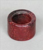 A Chinese carved red jade archers ring Of plain circular section. 3.5 cms wide. Generally in good