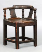 An 18th century child`s oak corner chair The arched back above a turned upright flanked by twin