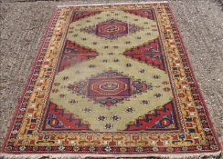 A Caucasian wool rug The sage green field enclosing twin medallions interspersed with rosettes,