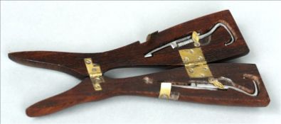 A 19th century rosewood cased pair of boot pulls The brass mounted case formed as leg. 30.5 cms