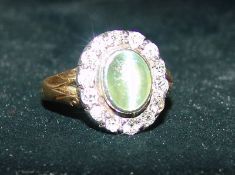 An unmarked gold moonstone and diamond ring The central cabochon moonstone bordered by a row of