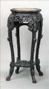 A late 19th/early 20th century Chinese carved hardwood jardiniere stand The marble inset top above