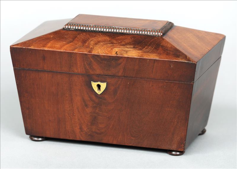 An early Victorian mahogany tea caddy Of sarcophagus form, the hinged cover enclosing twin lidded