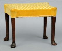 An 18th century walnut stool The shaped overstuffed seat standing on tapering legs with pad feet. 57