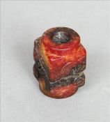 A Chinese carved green and rust jade toggle Of square section with incised decoration. 3.5 cms long.