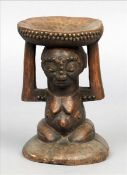 An African tribal carved hardwood stool The dished top supported by a carved female figure with