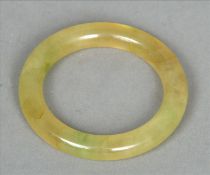 A Chinese carved green jade bangle Of plain circular section. 8 cms diameter. Generally in good