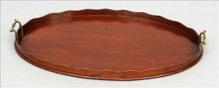 A Victorian mahogany tray The oval body with a serpentine gallery and twin brass carrying handles.