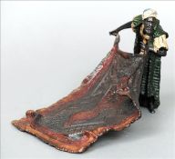 A Bergman style cold painted bronze model of a carpet seller Modelled unfurling his wares. 23 cms