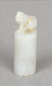 A 19th century Chinese slender white jade seal Of cylindrical form and mounted with a beast;