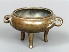 A Chinese bronze twin handled censor The scroll handles cast with flowerheads, standing on three