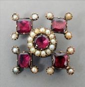 A Victorian unmarked yellow metal brooch The diamond shaped body set with garnets and seed pearls.