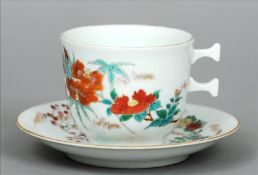 A Chinese porcelain cup and saucer The cup with unusual handle, both decorated with floral sprays,
