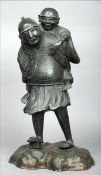 A large Japanese patinated bronze figural group Formed as a gentleman wearing a kimono with a