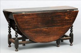 A 17th century oak gate-leg table The oval twin flap top above a plain frieze, standing on block and