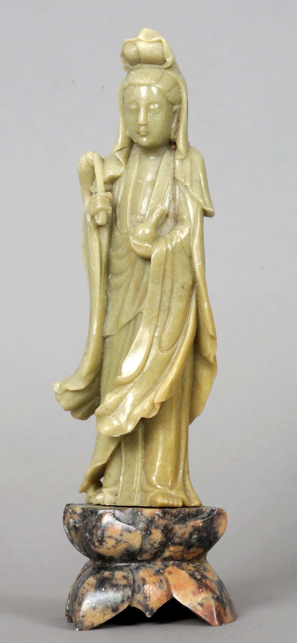 A Chinese carved soapstone figure of Guanyin Modelled holding a bottle and a fly whisk, standing