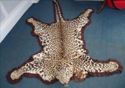 An early 20th century leopard skin rug, circa 1900 The detached head with inset glass eyes and