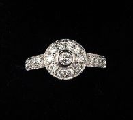 An 18 ct white gold and diamond ring With central target setting above stone set shoulders. 1 cms