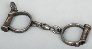 A pair of Victorian polished steel handcuffs Of typical form. 24 cms wide. Some pitting and wear,