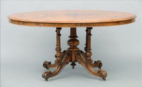 A Victorian inlaid burr walnut loo table The oval top with bands of inlay above a carved five column