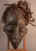 A carved African tribal mask With carved geometric decoration and rope twist hair. 35 cms high.