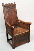 An 18th century fruitwood lambing chair The shaped top rail above the panelled back issuing twin