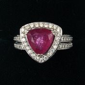 A modern 14 ct white gold ruby and diamond ring The triangular central ruby bordered by a single row