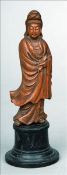 A Chinese carved wood figure of Guanyin Typically modelled, standing on an ebonised plinth base.