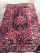 An Anjan wool rug The wine red field enclosing a central stepped medallion with pendant palmettes