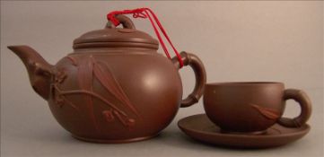 A Chinese Yixing pottery teapot and cover With applied foliate sprays; together with six tea cups