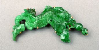 An unmarked gold mounted jade brooch Formed as a dragon. 5 cms wide. Overall good, some slight
