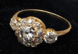 An unmarked gold diamond ring With central flowerhead setting flanked by two further diamonds, the